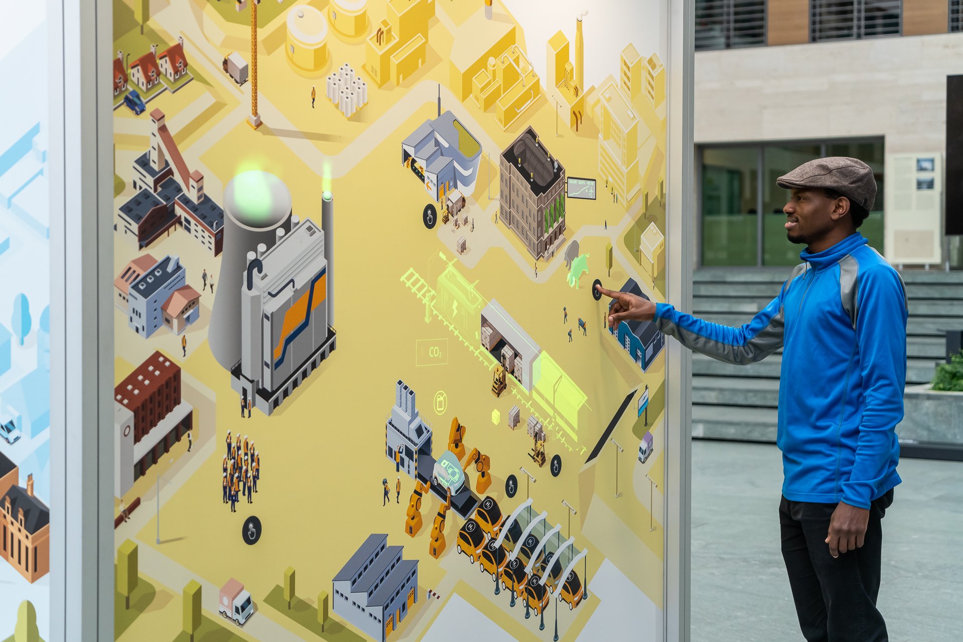A visitor starts up the animation at the Energy in Transition station and is fascinated by the light-up display of a freight train powered by electricity and an electric car on a production line.
